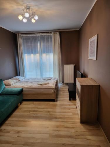 a bedroom with a bed and a couch and a window at AMBER APARTAMENT SZLAK 106 in Krakow