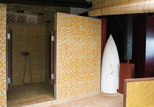 a bathroom with a surfboard on a tile wall at LE ROCHER DE TAHITI in Mariuti