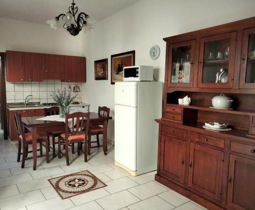 uma cozinha com uma mesa e um frigorífico branco em Casetta del’600 in antico ortale salentino em Maglie