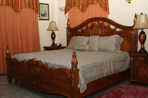 a bedroom with a large wooden bed with white sheets at PG Quality Inn in Georgetown