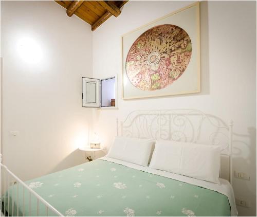 ein weißes Schlafzimmer mit einem Bett und einem Bild an der Wand in der Unterkunft Il Giardino di Lucia in Syrakus