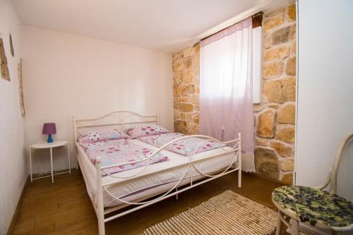 a bedroom with a white bed and a stone wall at Apartment Sanja in Pirovac