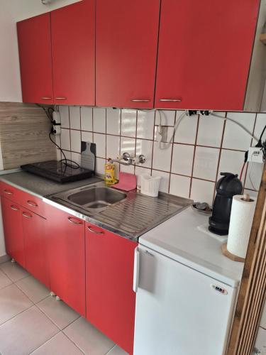 a small kitchen with red cabinets and a sink at Dora in Sremski Karlovci