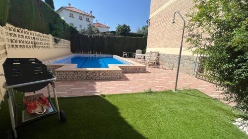 una parrilla y una piscina en un patio en Casa Monte Verde con piscina a 10 min de Granada, en Cájar