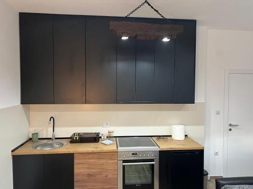 a kitchen with black cabinets and a sink at LiboroApartments in Niš