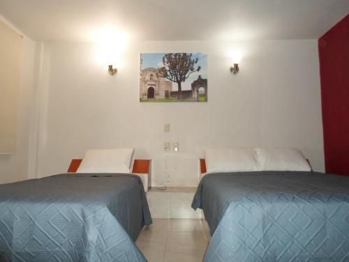 Habitación con 2 camas y una foto en la pared. en Hotel María Bonita, en Tlaxcala de Xicohténcatl