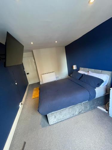 ein Schlafzimmer mit einem großen Bett mit blauen Wänden in der Unterkunft City Heights inquire for FREE Parking in Kent