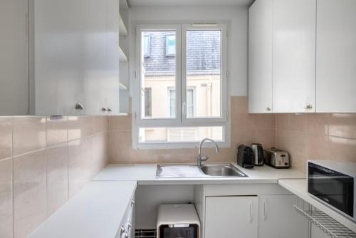 une cuisine blanche avec un évier et une fenêtre dans l'établissement Eiffel Tower / Tour Eiffel, à Paris