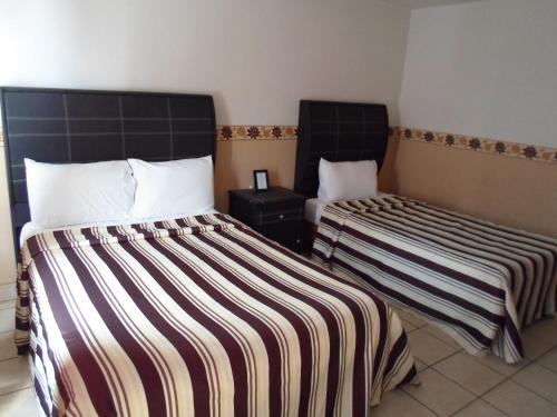 two beds with striped sheets in a room at Hotel María Bonita in Tlaxcala de Xicohténcatl