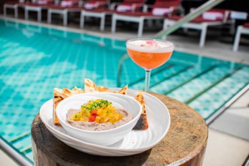 a bowl of food and a drink next to a pool at Virgin Hotels New Orleans in New Orleans