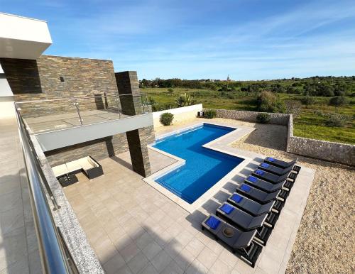a pool with lounge chairs next to a house at Luxury Modern Style Villa with Private Pool in Pêra