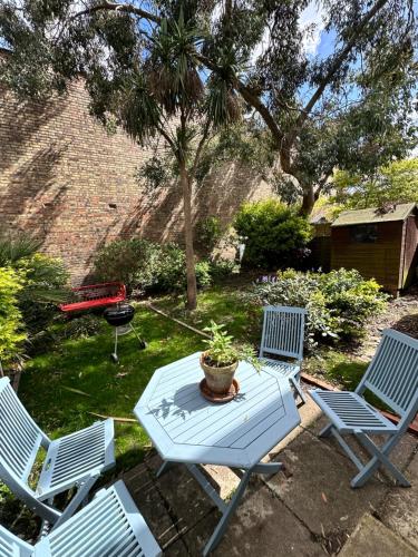 Charming, Renovated Residence in Willesden Green في لندن: فناء به ثلاثة كراسي وطاولة به نباتات الفخار