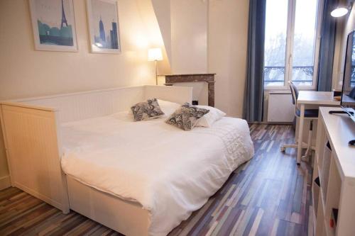 um quarto com uma cama branca com duas almofadas em Joli Studio Place Notre Dame em Pontoise