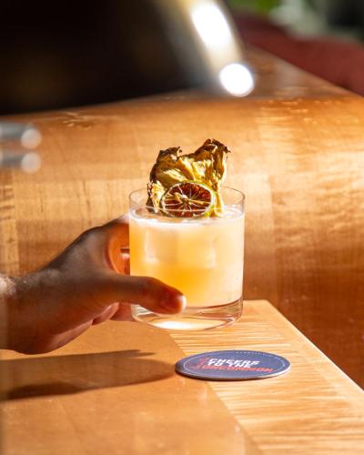 a person holding a glass of orange juice on a table at Virgin Hotels New Orleans in New Orleans