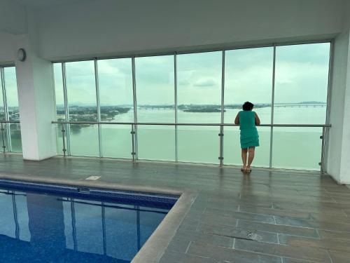 a woman looking out at the water from a swimming pool at Spacious 2 Bedroom Apartment with river views in Puerto Santa Ana River Front 2 in Guayaquil