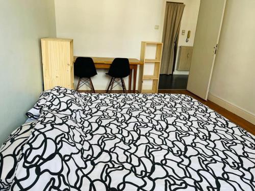a bedroom with a black and white bed and two chairs at Chand Mama in Chambéry