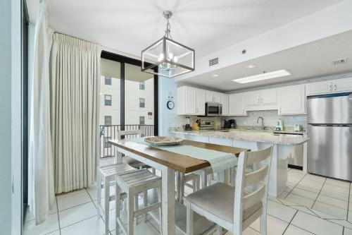 a kitchen with white cabinets and a wooden table and chairs at Phoenix VIII 81201 by Vacation Homes Collection in Orange Beach