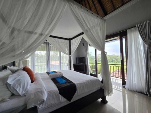 1 dormitorio con cama con dosel y balcón en Belvilla 93799 Kasuari Villa Three Bedroom At Taro Village Ubud en Penginyahan