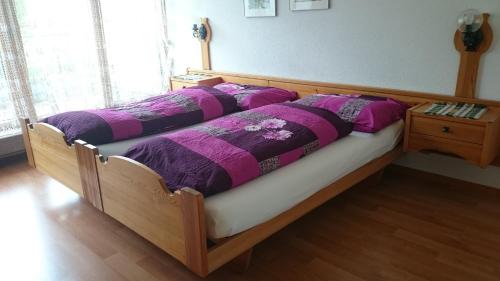 ein Holzbett mit lila Daunendecke darauf in der Unterkunft Tulai 104E in Scuol