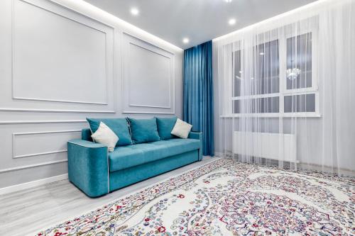 sala de estar con sofá azul y alfombra en 2 room apartament Barys arena, en Astana