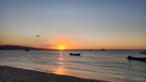 a sunset on the beach with a boat in the water at Villa Rosa in Punta Rucia