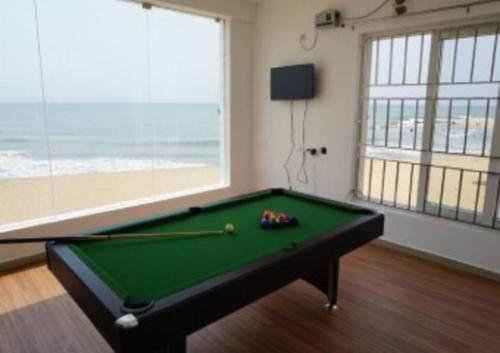 una mesa de billar en una habitación con una ventana grande en Beachfront Bliss: Beautiful Villa in Kovalam, en Covelong
