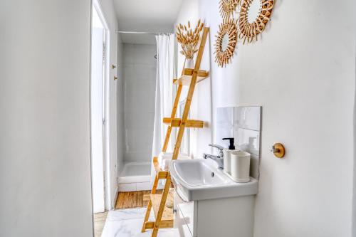 een badkamer met een witte wastafel en een houten ladder bij Le Sunrise Bohème - studio proche université Paris 13 in Villetaneuse