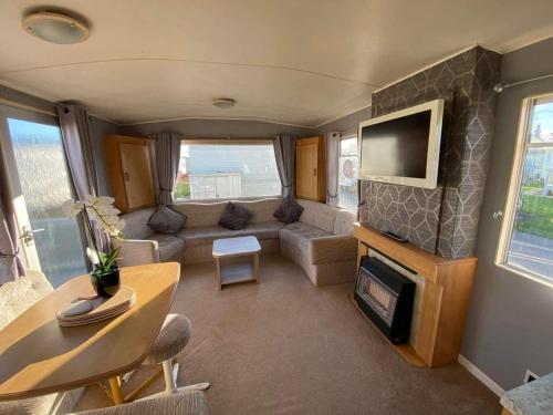 a living room with a couch and a tv at Seaview 203 - Ingoldmells, pet friendly, WiFi, bed linen and close Fantasy Island - Meadow Lakes Caravan & Lodge Hire in Ingoldmells