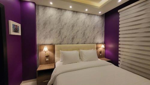 a bedroom with a large bed with purple walls at Western Gate Residence 2 Amman in Amman