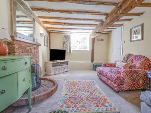 a living room with a couch and a tv at 3 The Almshouse in Saxmundham