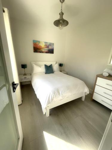a bedroom with a white bed and a dresser at Kathleen's Carrowkeel Cottage in Sligo