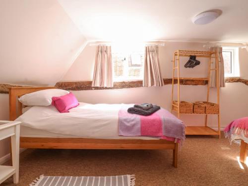 a bedroom with a bed with white sheets and pink pillows at 3 The Almshouse in Saxmundham