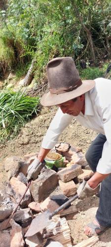 a man wearing a hat constructing a fire pit at Albergue Las Abejitas in Chancos