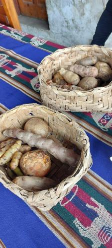 two baskets filled with potatoes and vegetables on a table at Albergue Las Abejitas in Chancos