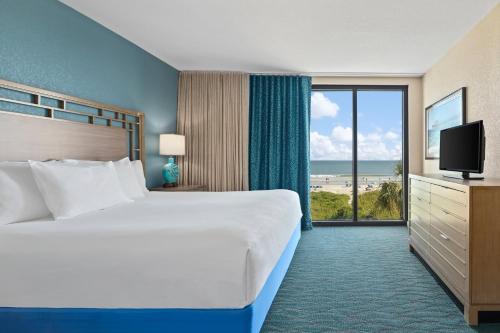 マートルビーチにあるClub Wyndham Westwindsのベッドと大きな窓が備わるホテルルームです。