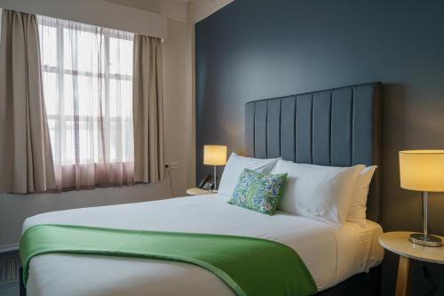 a bedroom with a large bed with a green headboard at Ibis Styles Invercargill in Invercargill