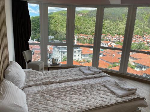 a bedroom with a bed and a large window at Apartmani Vidikovac in Prijepolje