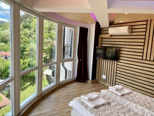 um quarto com janelas grandes e uma cama com toalhas em Apartmani Vidikovac em Prijepolje