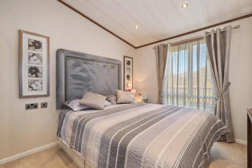 a bedroom with a bed with a large window at Cormorant - Luxury Lodge Close to the Beach in Tenby