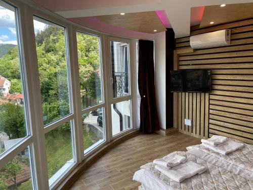 a room with two beds and a tv and windows at Apartmani Vidikovac in Prijepolje