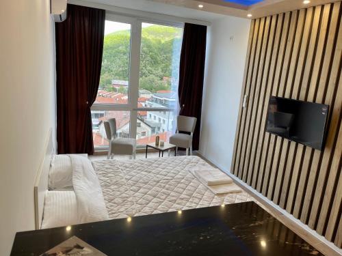 a hotel room with a bed and a television and a balcony at Apartmani Vidikovac in Prijepolje
