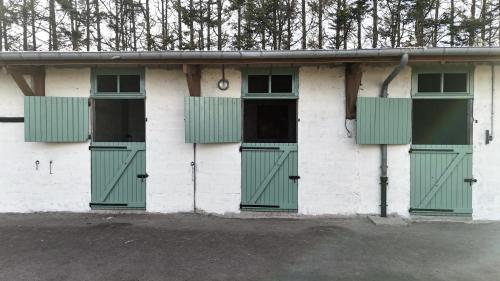 a white building with green doors and windows at Domaine des cyprès in Vaudrimesnil