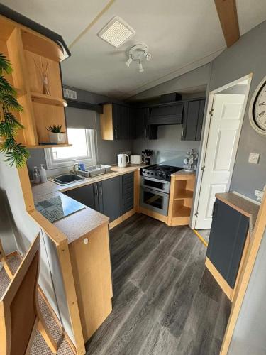 a kitchen with wooden cabinets and a stove top oven at Sealands 29 - Ingoldmells, pet friendly, bed linen & close to fantasy island - Meadow Lakes Caravan & Lodge Hire in Ingoldmells