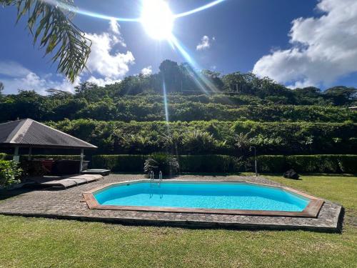 una piscina en un patio con una montaña al fondo en Bungalow Tipanier - Vue parfaite en Tevaitoa
