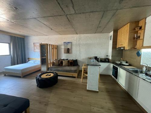 eine Küche und ein Wohnzimmer mit einem Sofa und einem Bett in der Unterkunft Teia-AJ in Praia