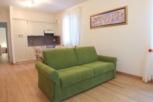 a green couch in a living room with a kitchen at Villa delle Rose in Portogruaro