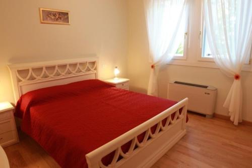 1 dormitorio con 1 cama grande con colcha roja en Villa delle Rose, en Portogruaro