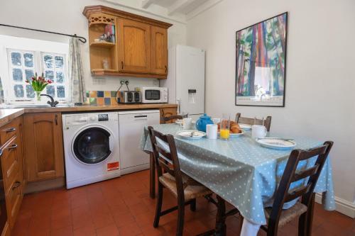 a kitchen with a table and a washing machine at Rose Cottage in Pwllheli