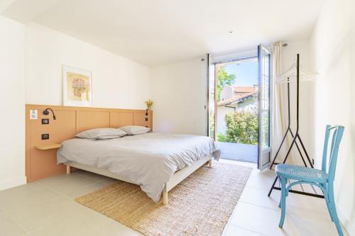 a bedroom with a bed and a blue chair at La Conciergerie Biarritz in Biarritz