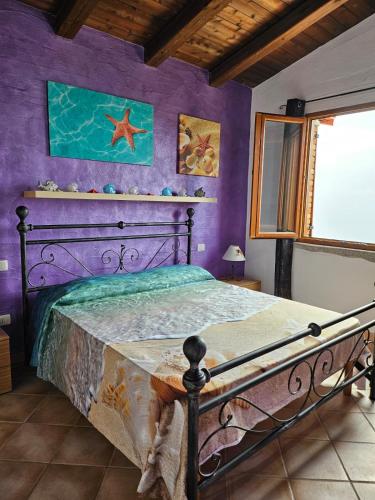 a bedroom with a bed with a purple wall at La Perla e le Conchiglie Tanca Piras vista mare in Nebida